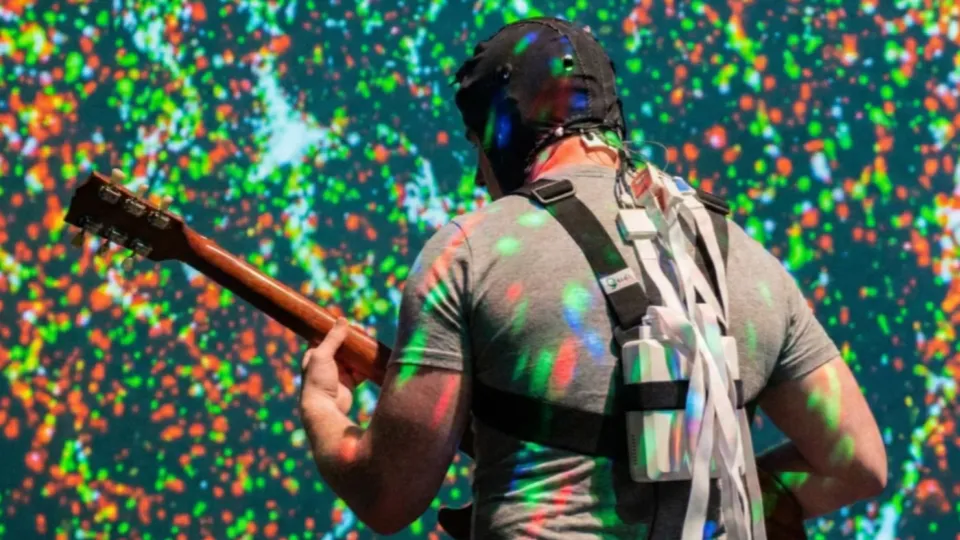 Torin Hopkins, seen from behind, playing guitar in an fNIRS brain-imaging cap during a Stringesthesia performance